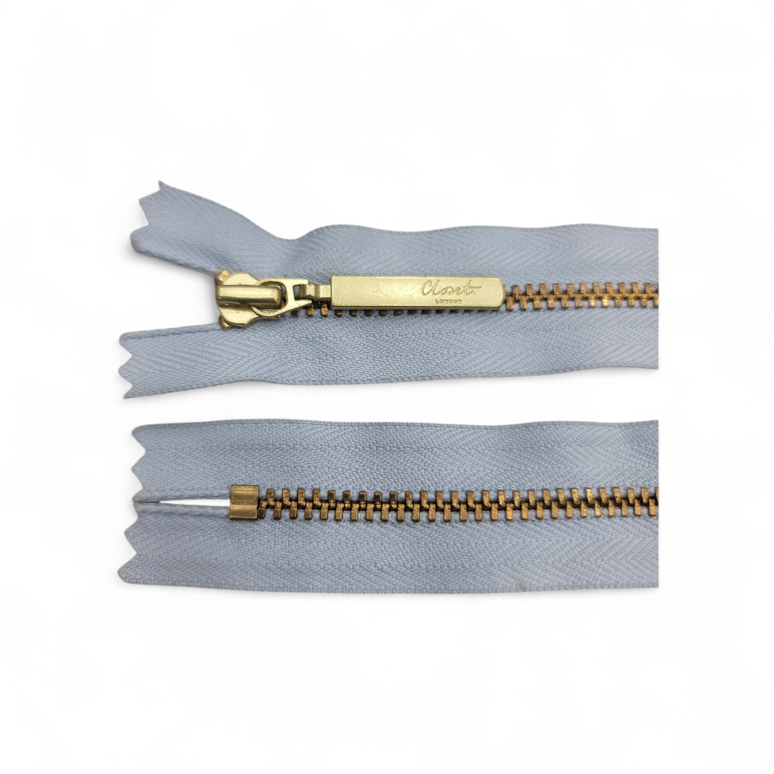 YKK closed end gold metal zipper with grey fabric.