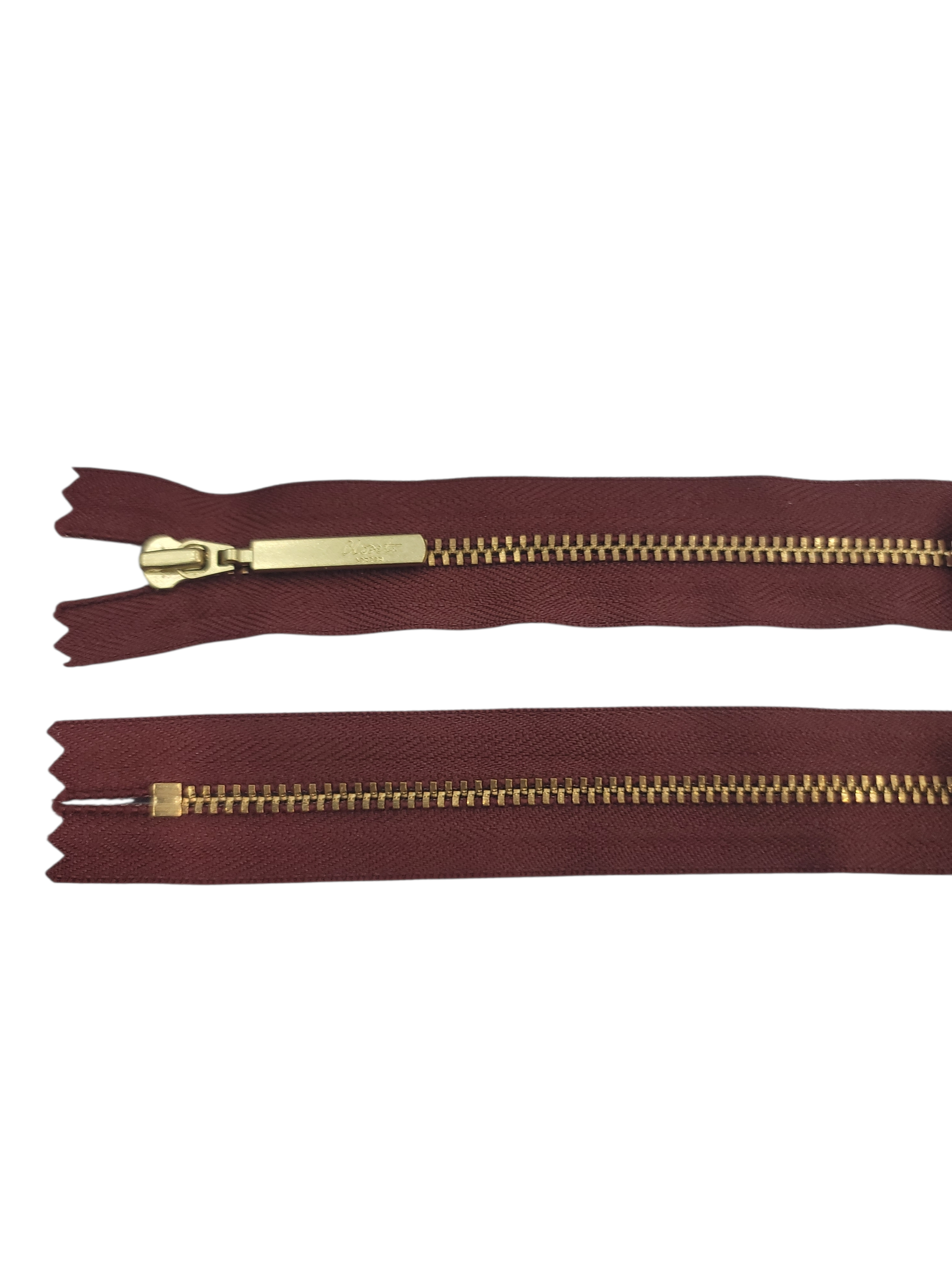 YKK size 3 closed end gold metal zipper on maroon fabric.