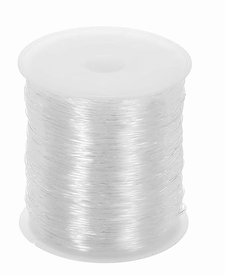 A spool of clear, thin elastic cord for jewelry making on a white plastic reel.