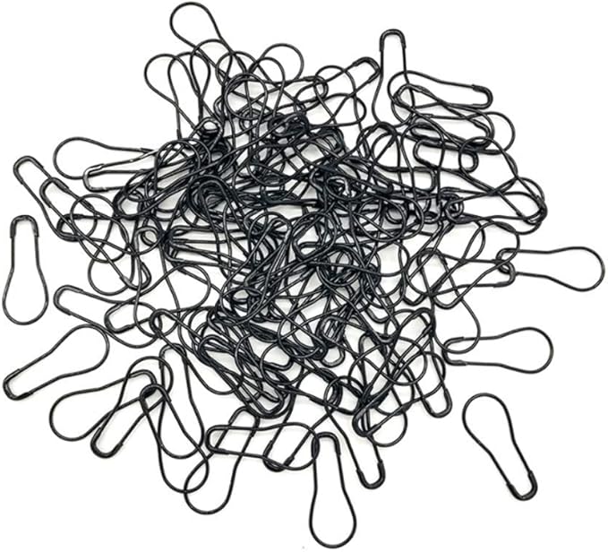 A pile of black metal bulb-shaped safety pins scattered on a white background.