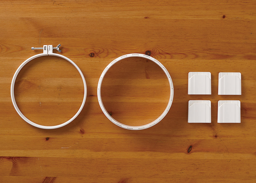 Clover Punch Needle Hoop set with white plastic rings and four height-adjustment legs on wood.
