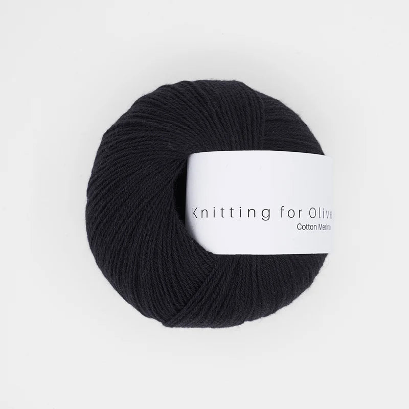 A ball of black Knitting for Olive Cotton Merino yarn with a white paper label.