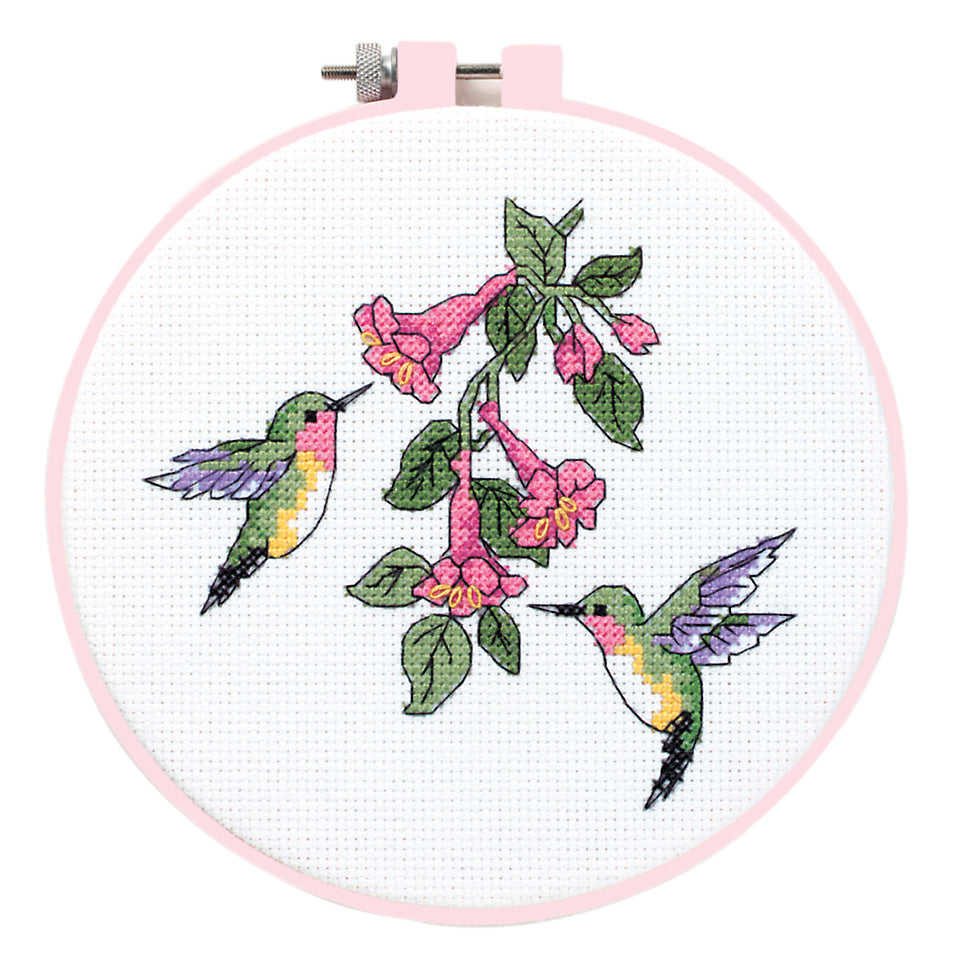 Counted cross stitch kit featuring two hummingbirds and pink flowers in a pink embroidery hoop.