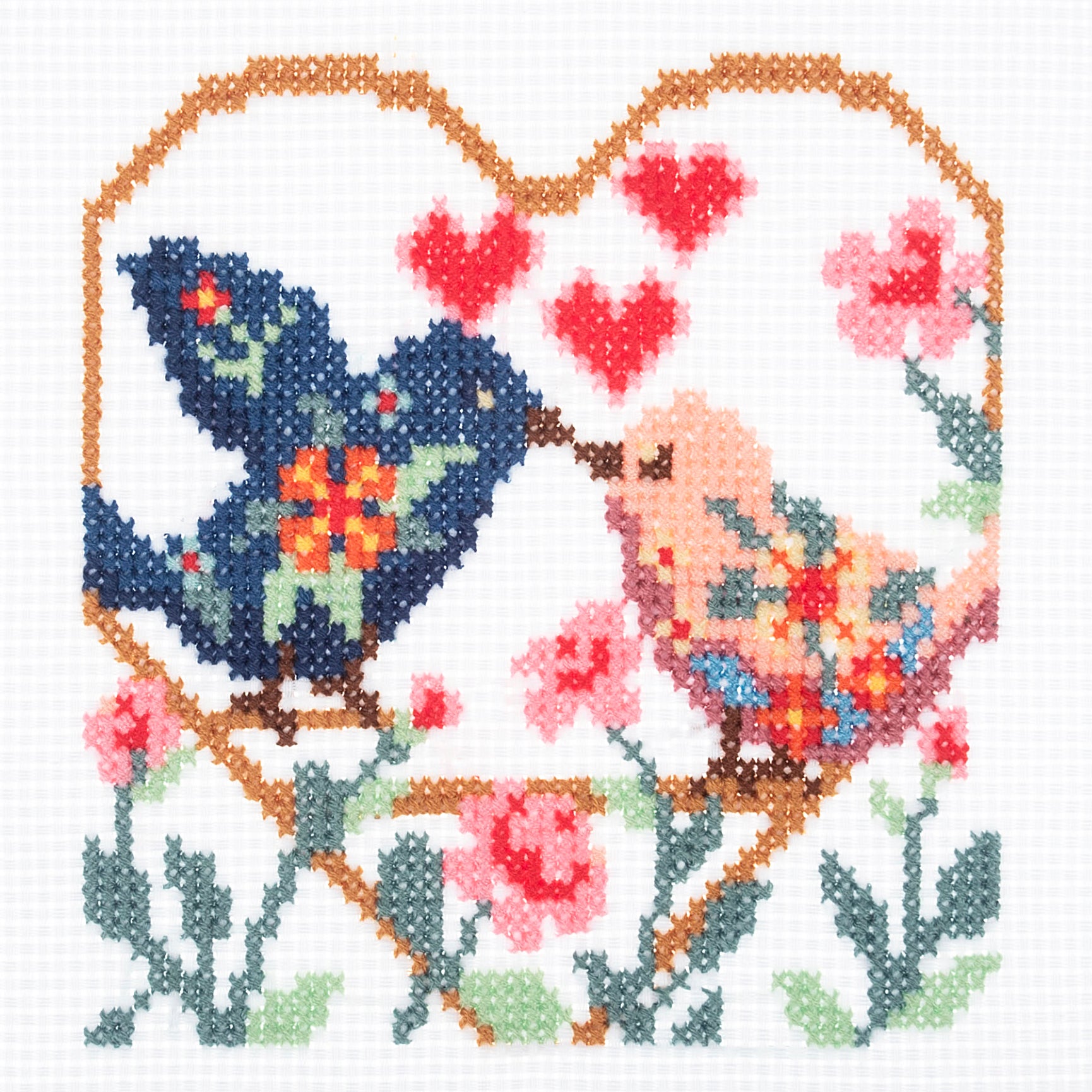 Counted cross stitch kit featuring two colorful birds inside a heart-shaped border with flowers.