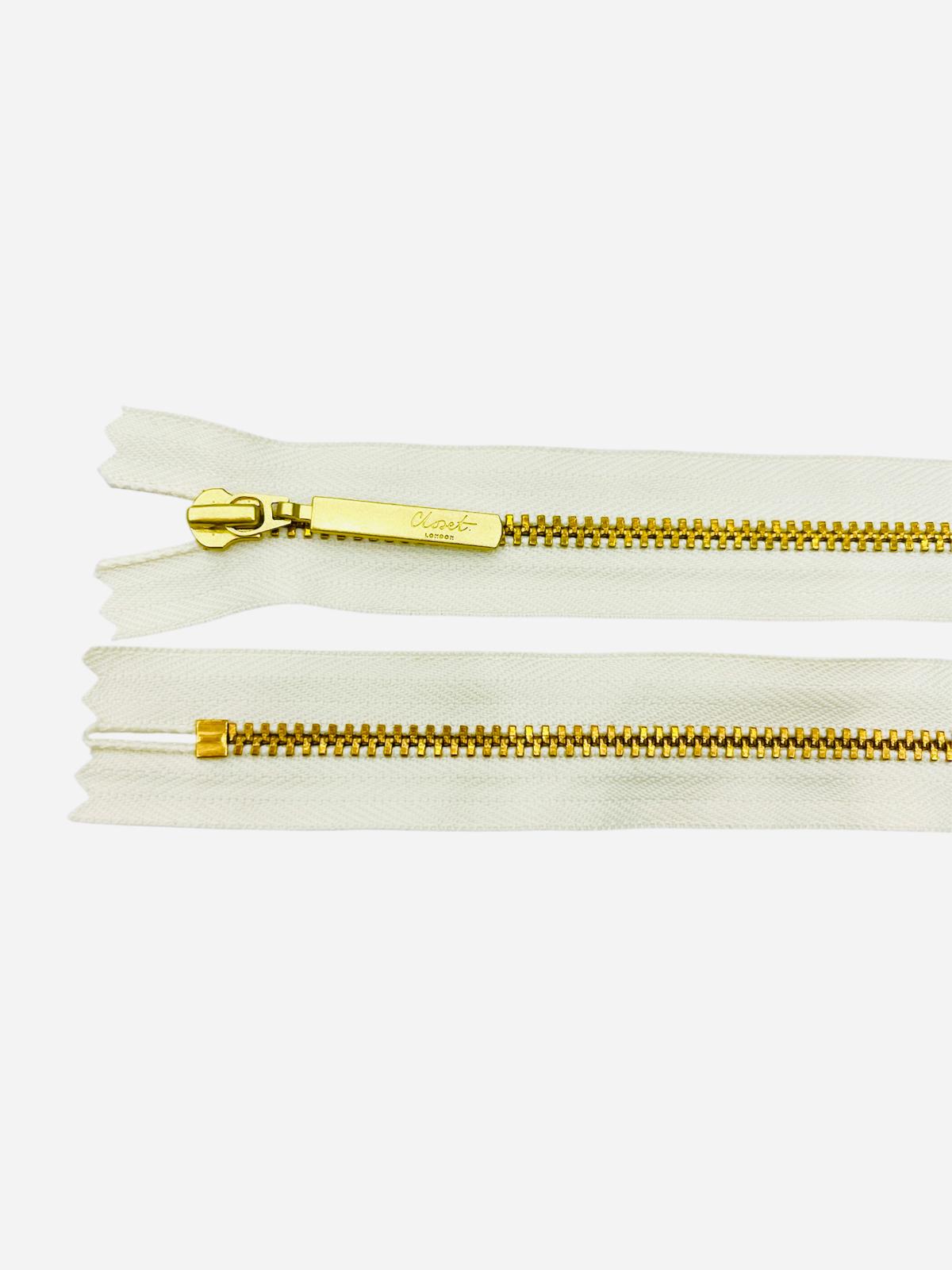 YKK Size 3 closed end gold metal zip with white tape.