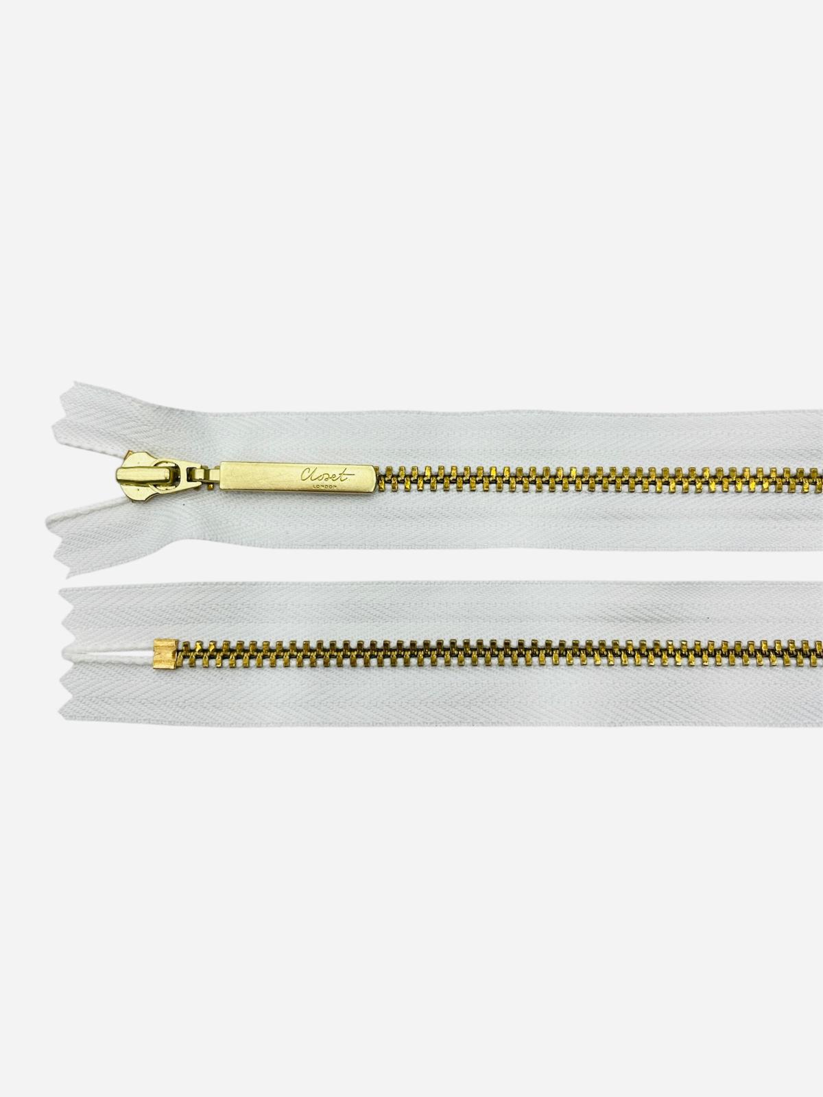 YKK Size 3 closed end gold metal zipper with white tape.