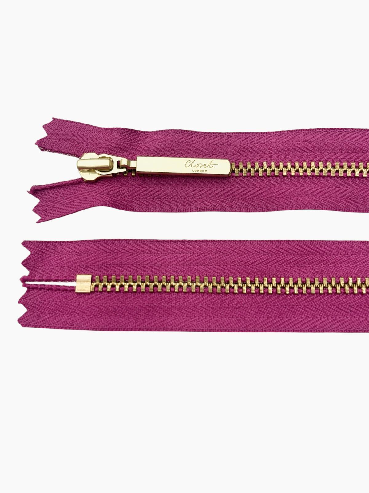 YKK size 3 closed end gold metal zipper on magenta fabric.