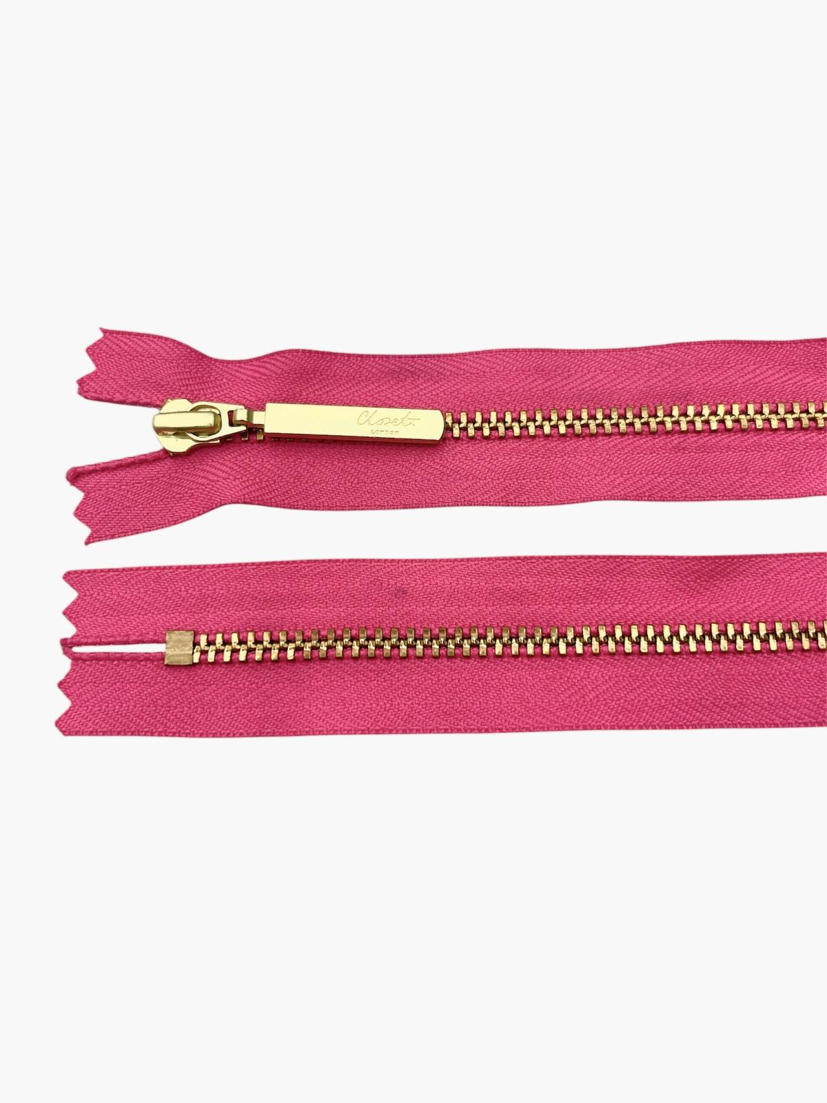 YKK size 3 closed end gold metal zip with pink tape.