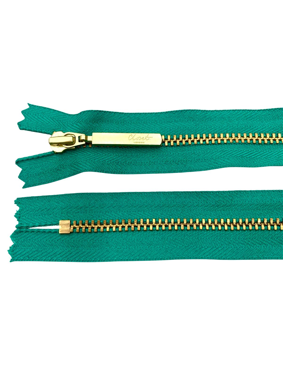 YKK size 3 closed end gold metal zipper on teal fabric.