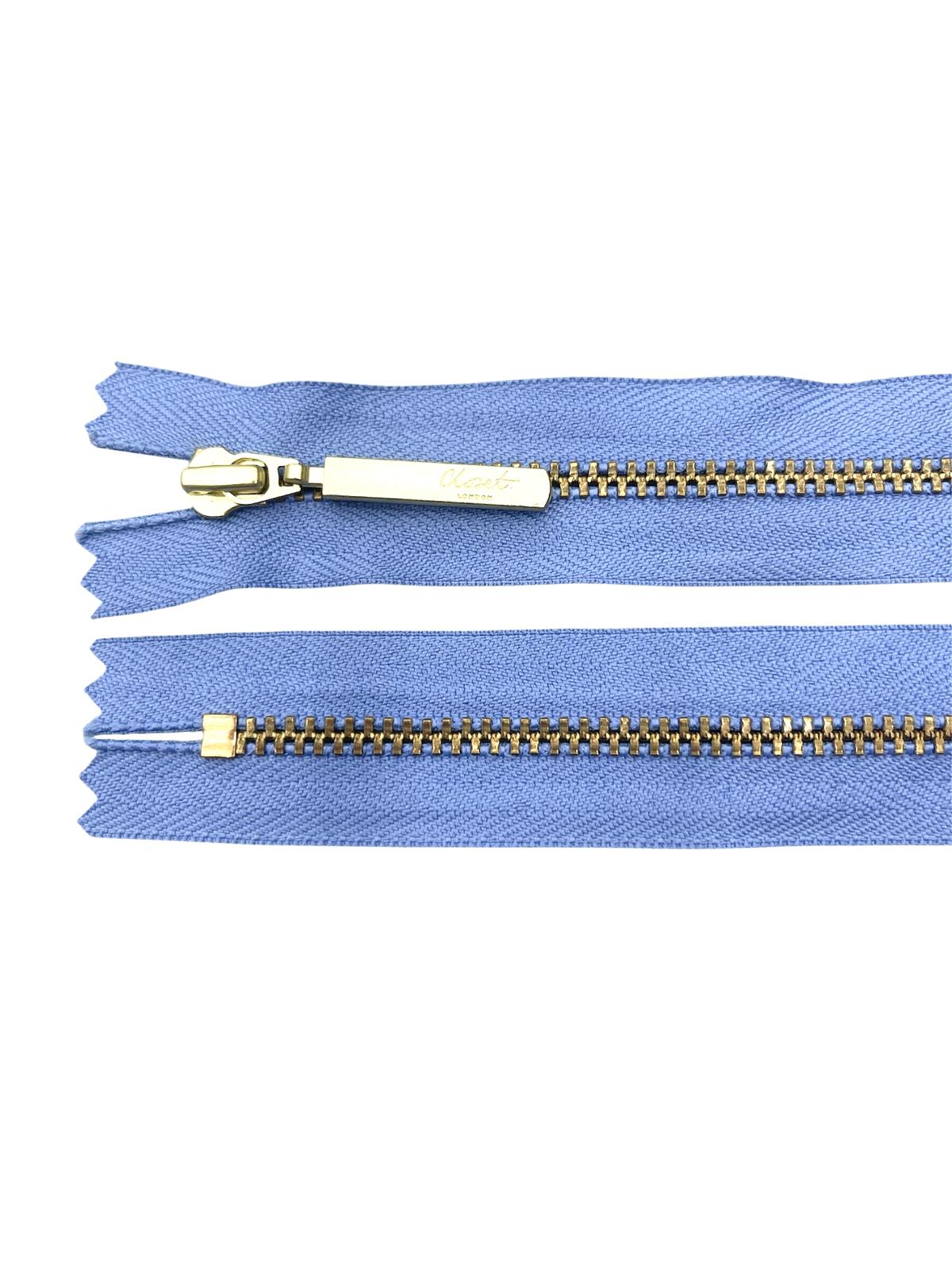YKK size 3 closed end gold metal zip on blue fabric.