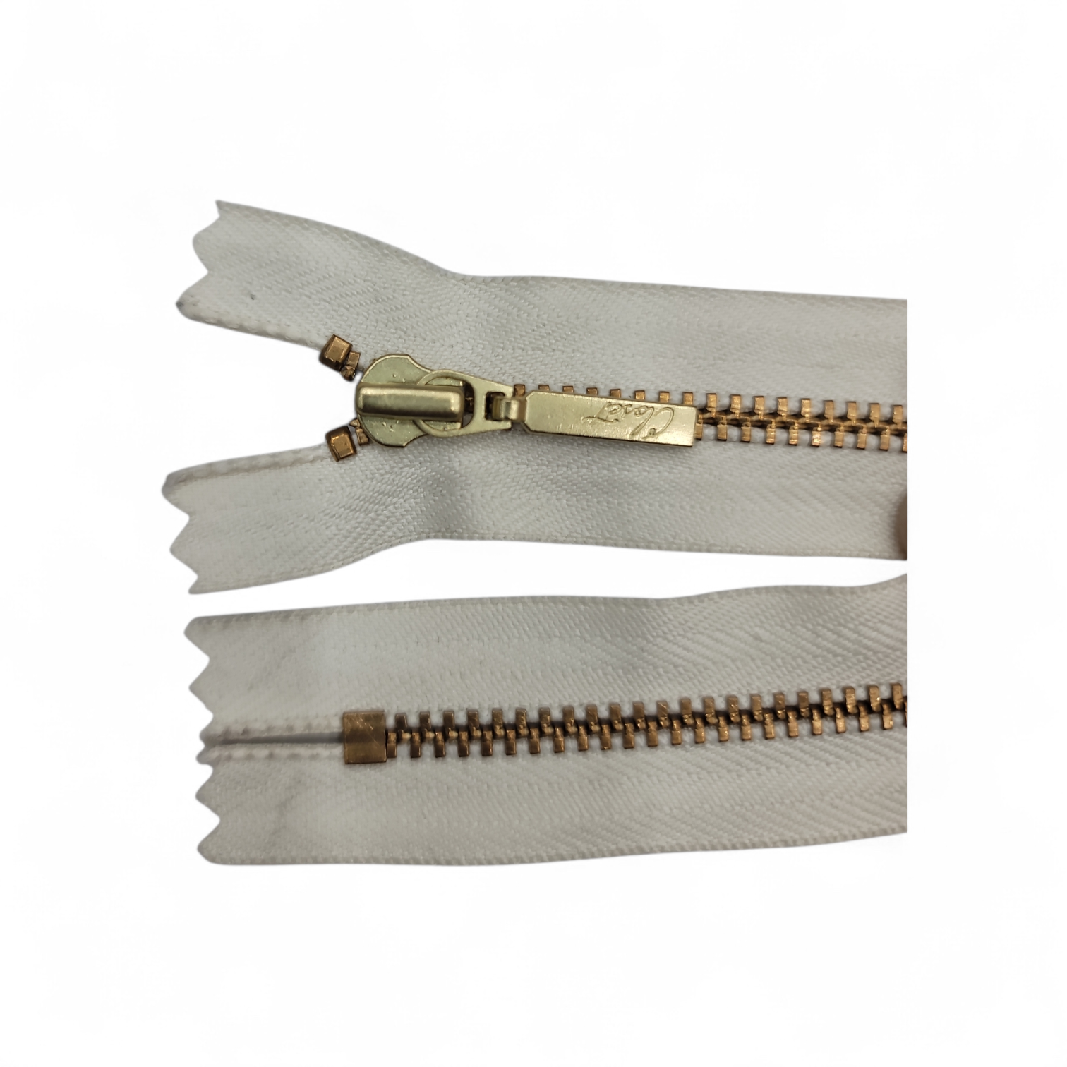 YKK size 3 closed end gold metal zipper with white tape.