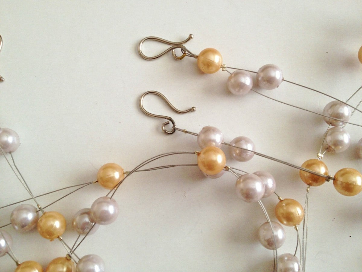 Multi-strand wired curtain tie backs featuring ivory and gold faux pearls with silver metal hooks.
