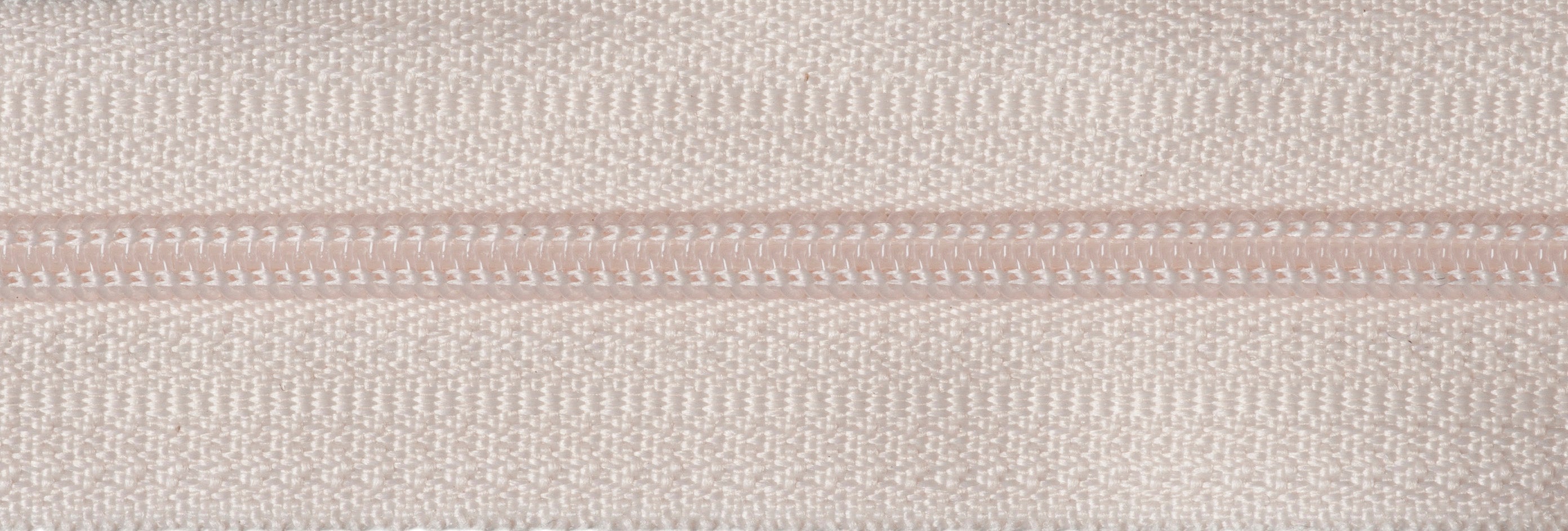 Close-up of a cream-colored endless nylon coil zip with polyester tape.