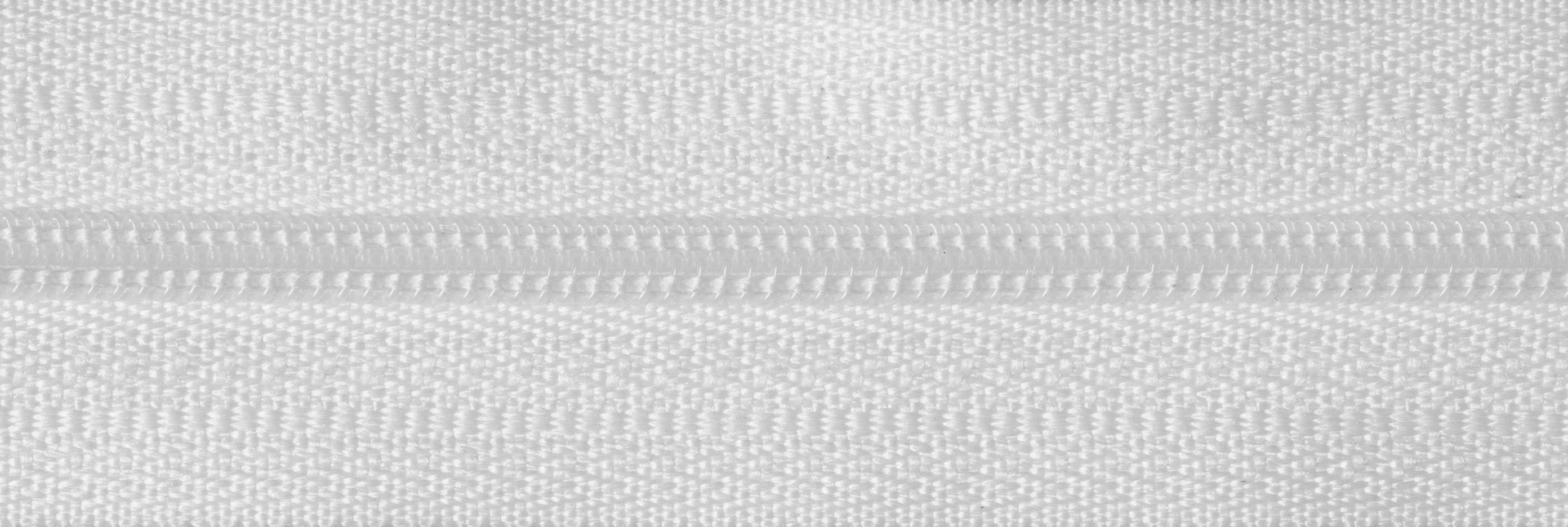 Close-up of a white lightweight nylon coil zip with polyester tape for soft furnishings.