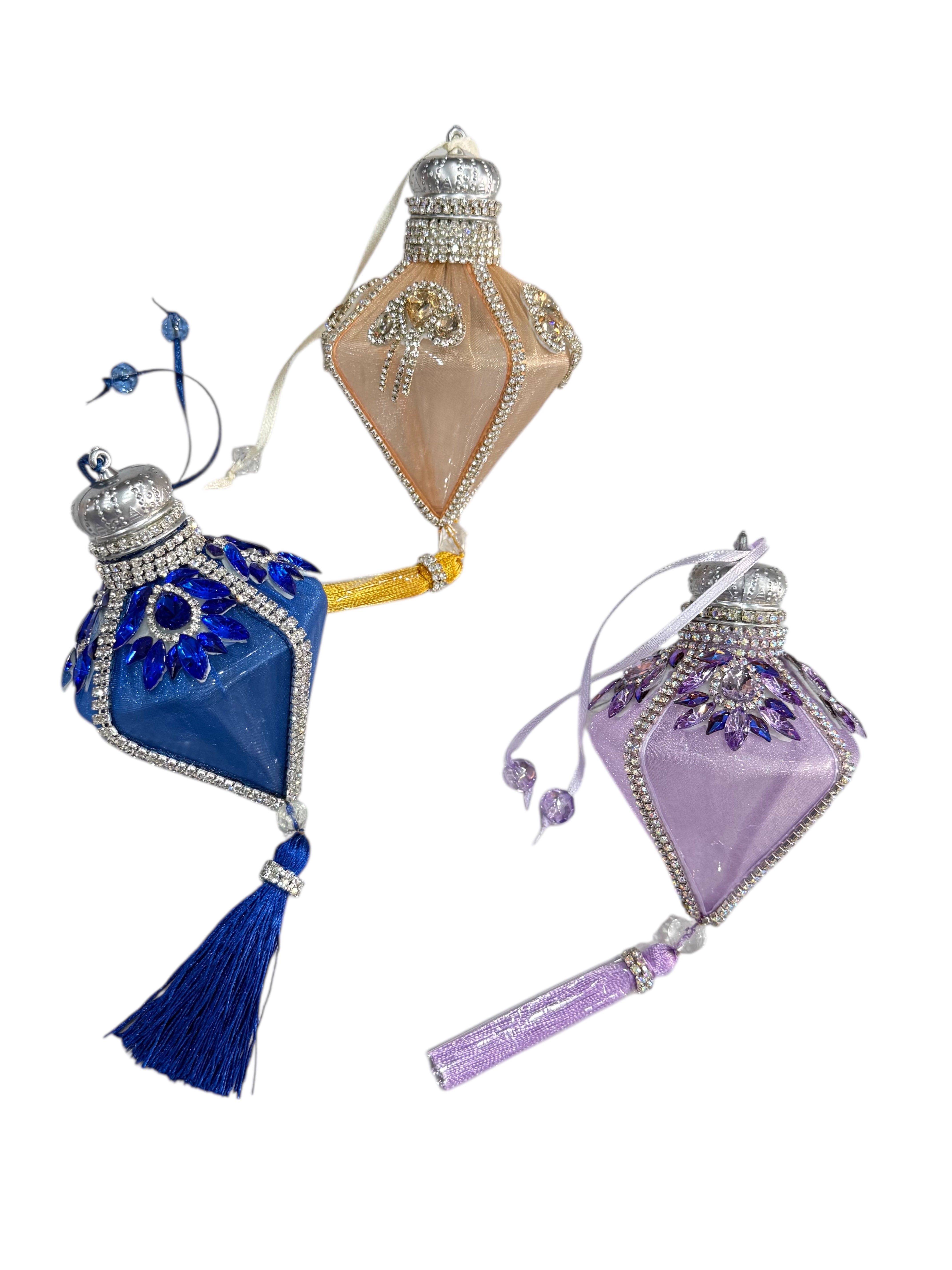 Three diamond-shaped Christmas ornaments with tassels and jeweled crowns.