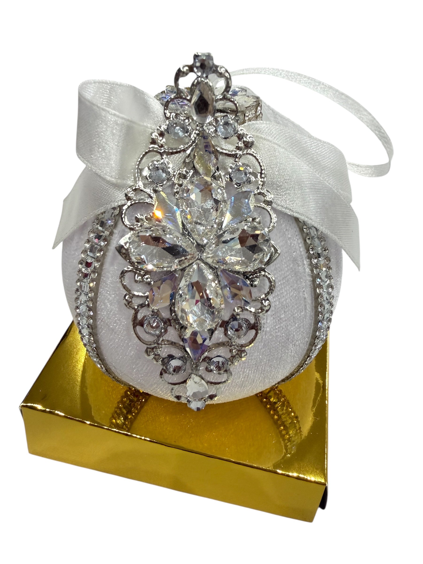 White round ornament with silver and crystal embellishments on a gold box.