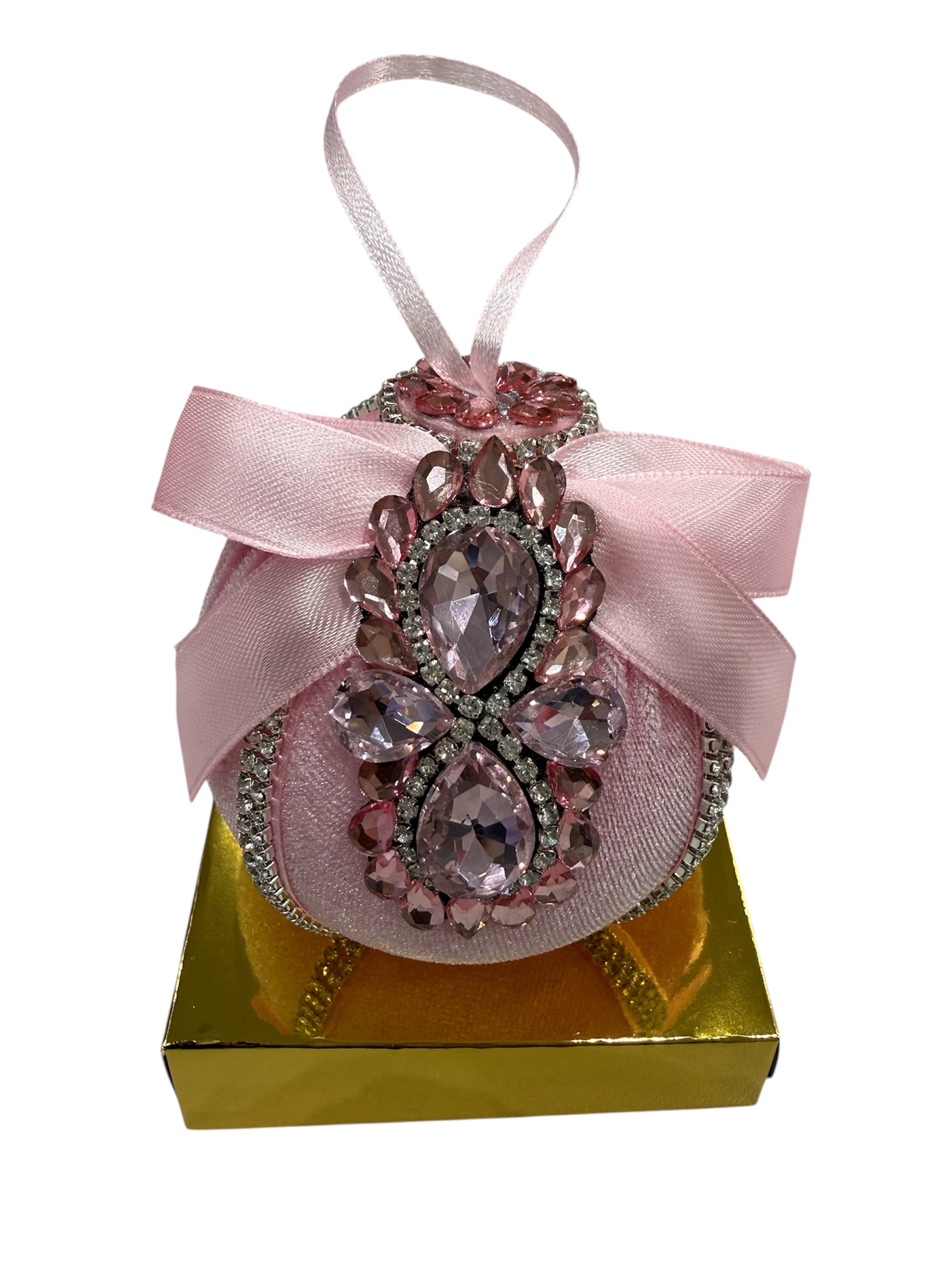 Pink round Christmas ornament with rhinestones and a bow on a gold box.
