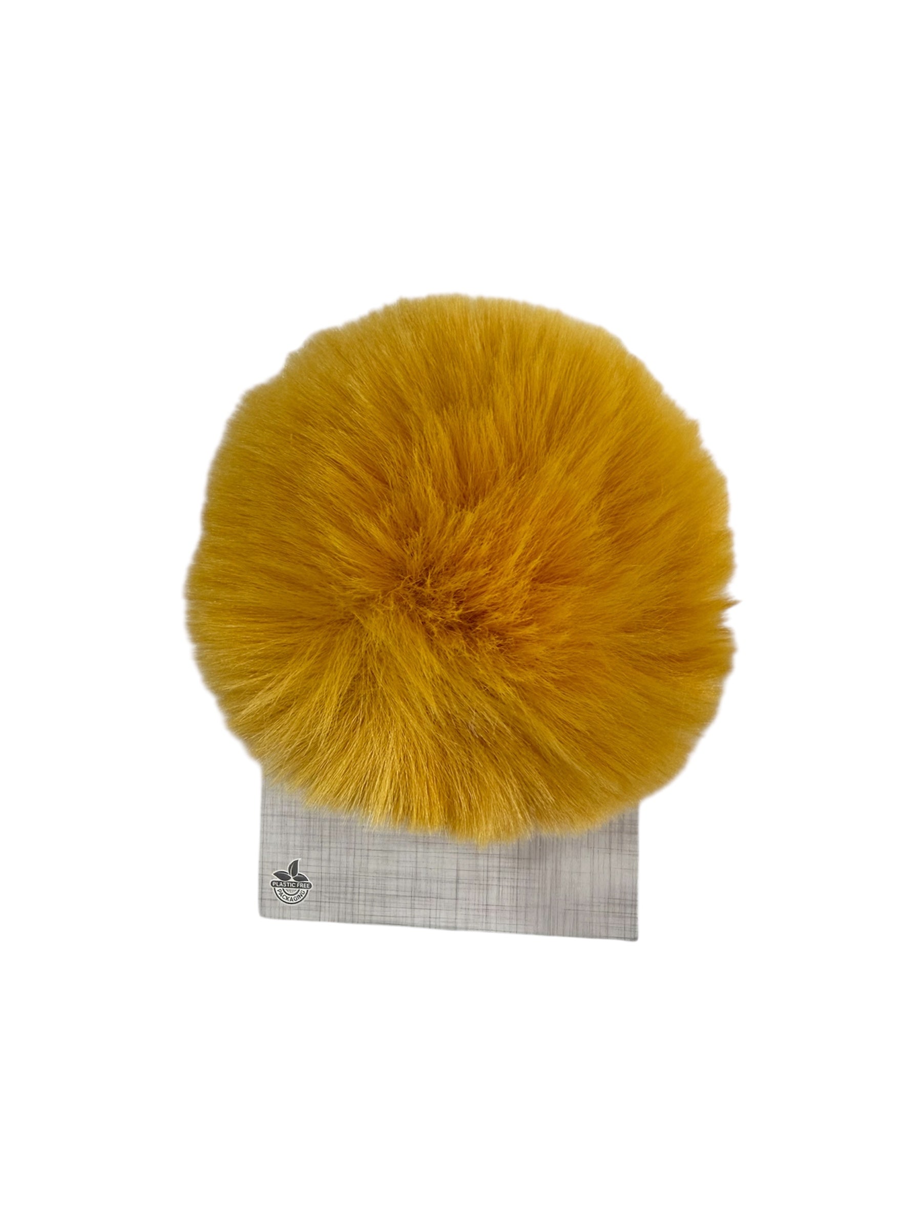 A yellow faux fur pompom sits on a grey patterned card with a "plastic free packaging" logo.