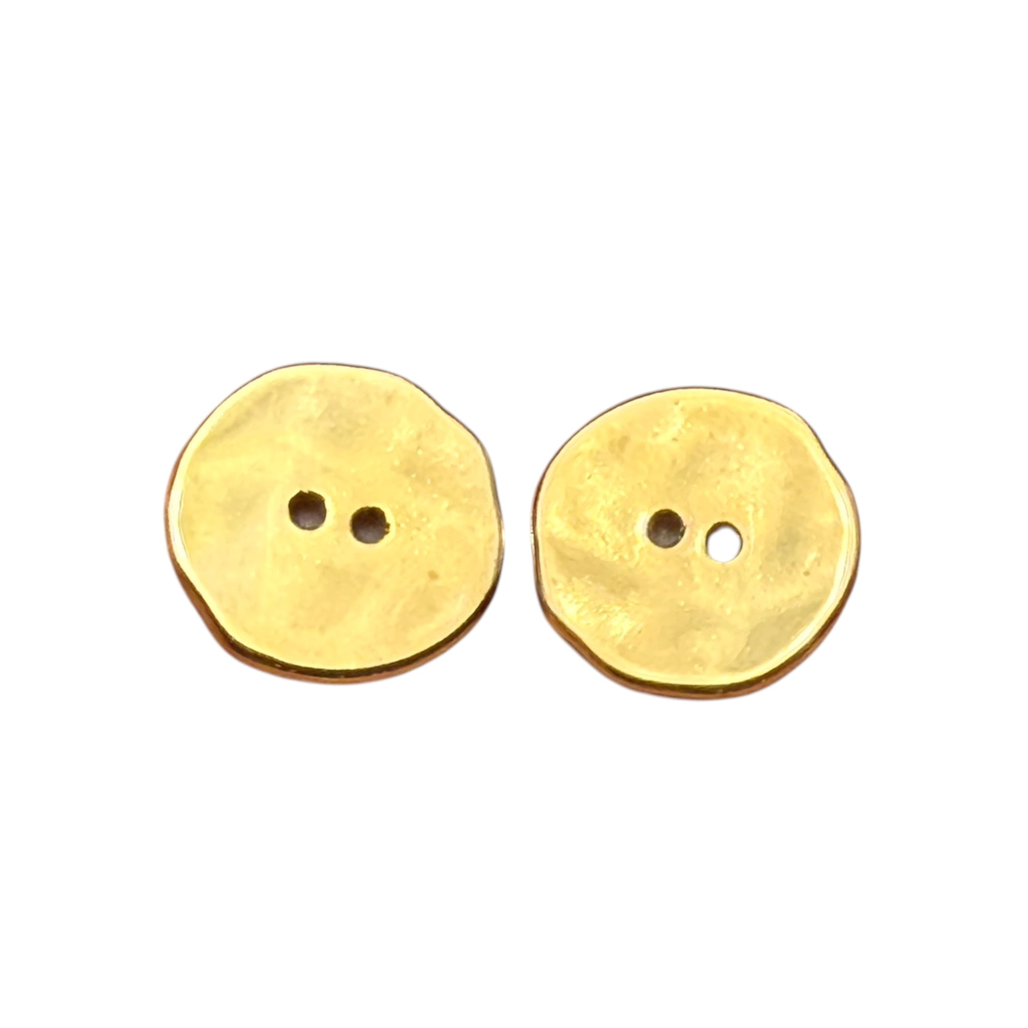 Two round, unevenly shaped gold buttons with two holes each on a white background.