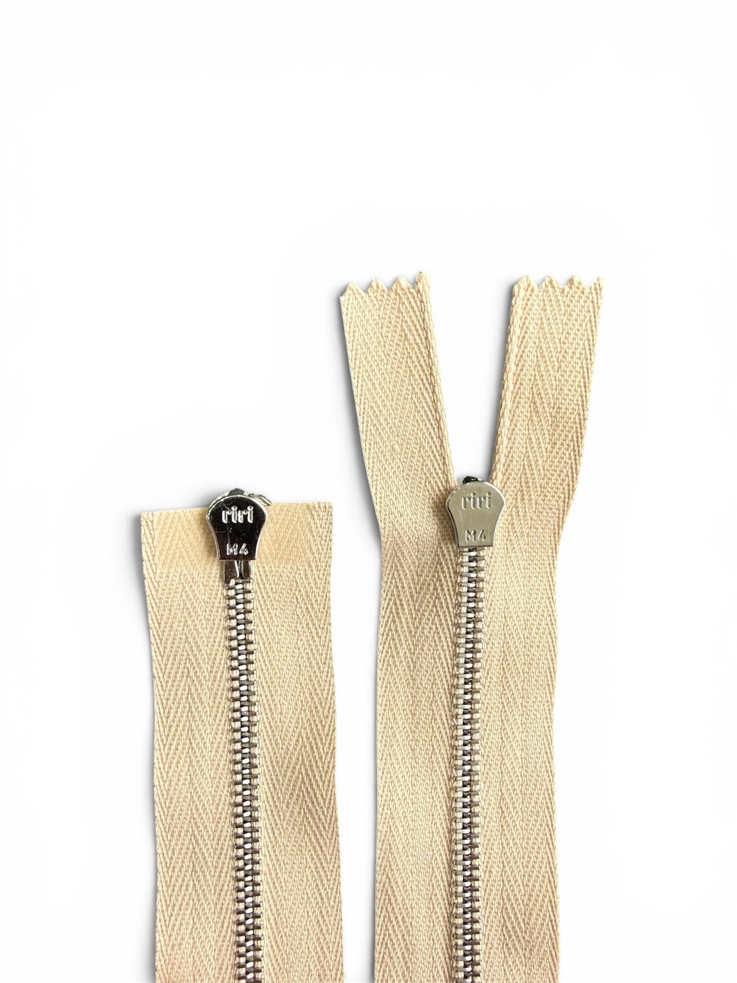 Two Riri cream zippers with silver metal teeth and M4 sliders on a white background.