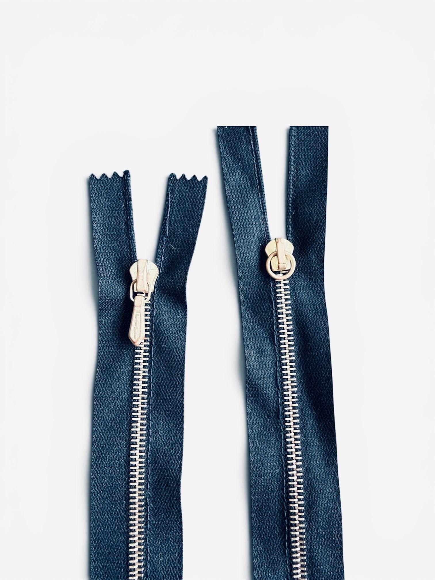 Two Riri 65cm two-way metal zippers with navy blue tape and polished rose gold teeth.