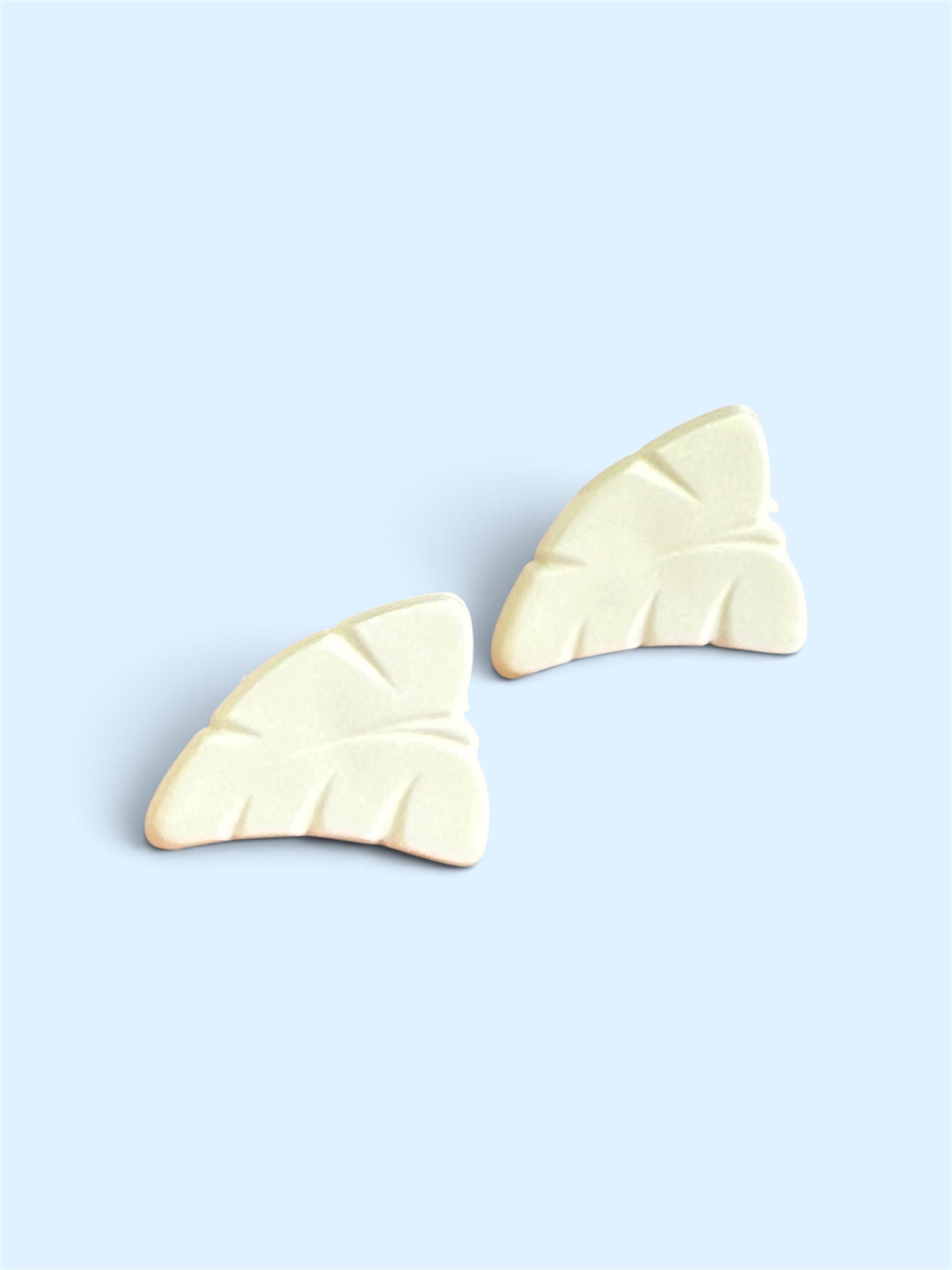 Two 12mm white leaf-shaped buttons with carved vein details on a light blue background.