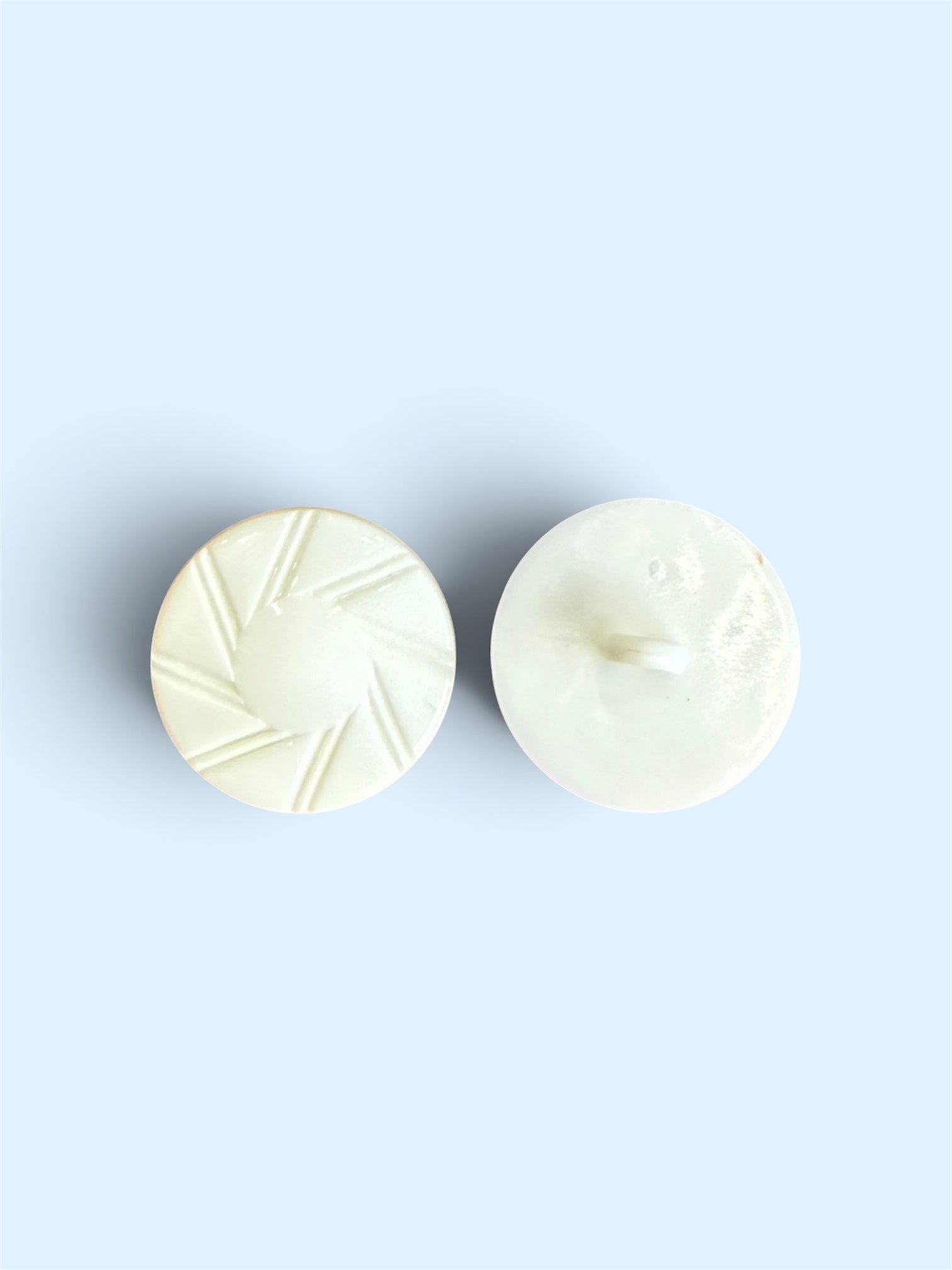 Two 21mm white round buttons, one showing a textured sunburst pattern and one showing the shank back
