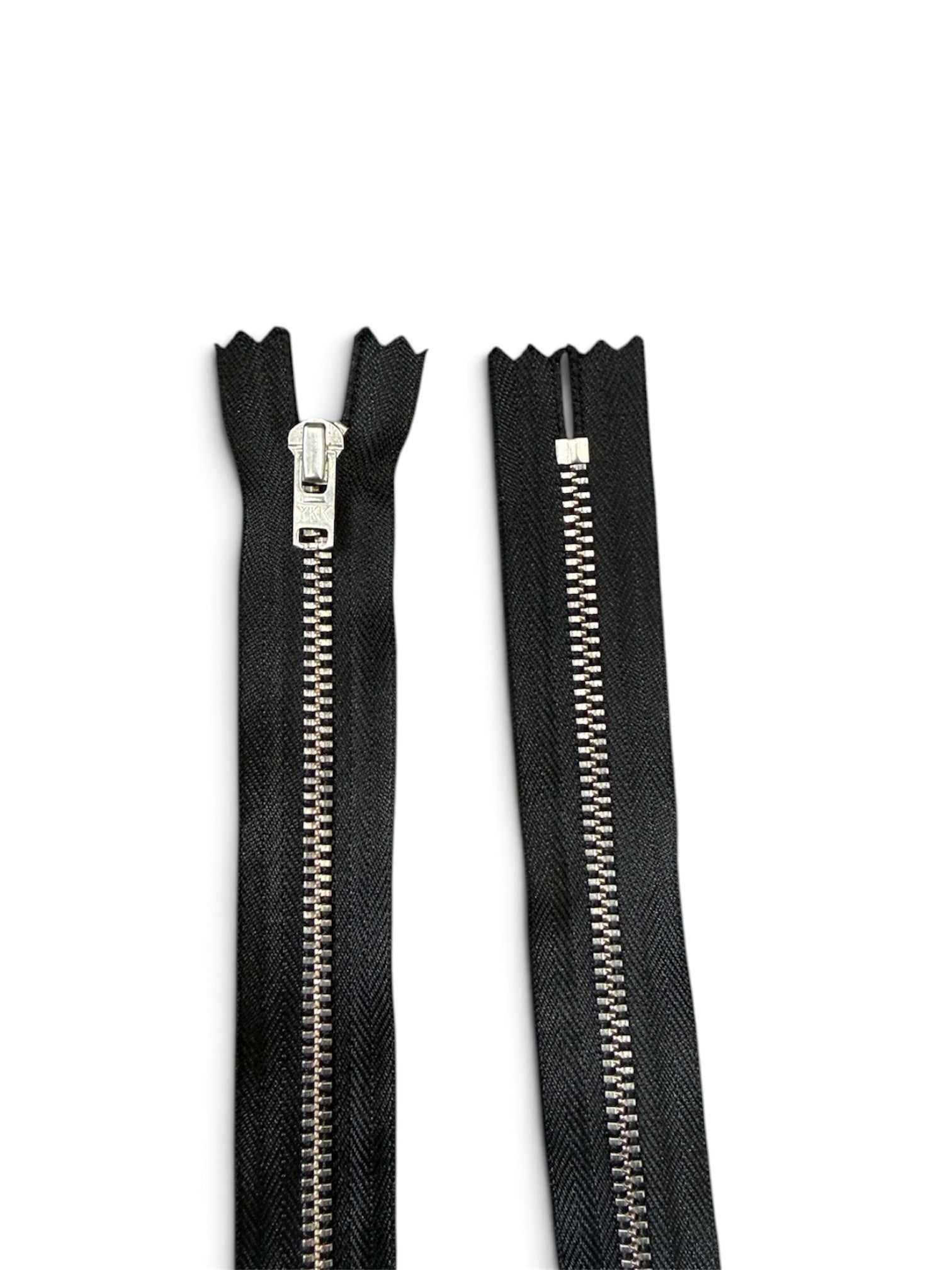 YKK 56cm black zipper with wide tape and silver metal teeth shown in a closed-end design.