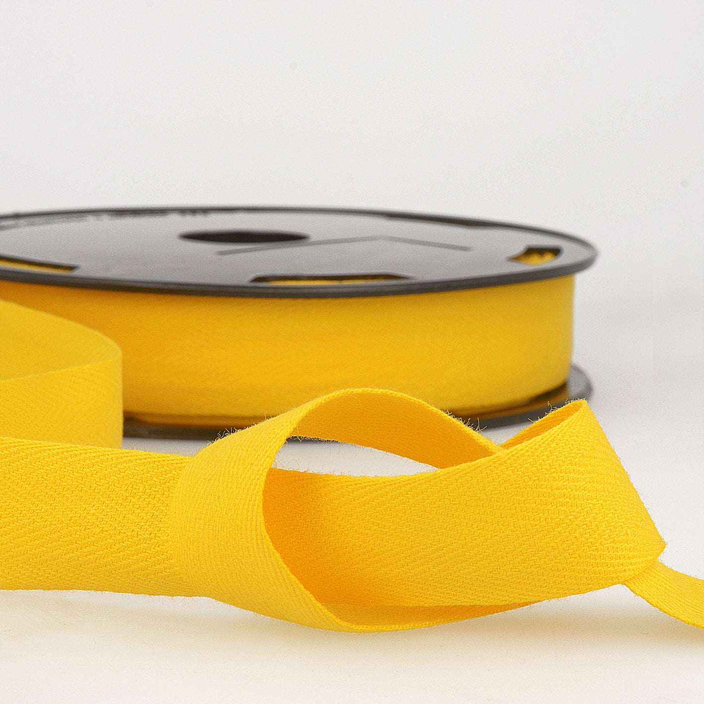 A roll of bright yellow cotton twill tape with a visible herringbone weave pattern.