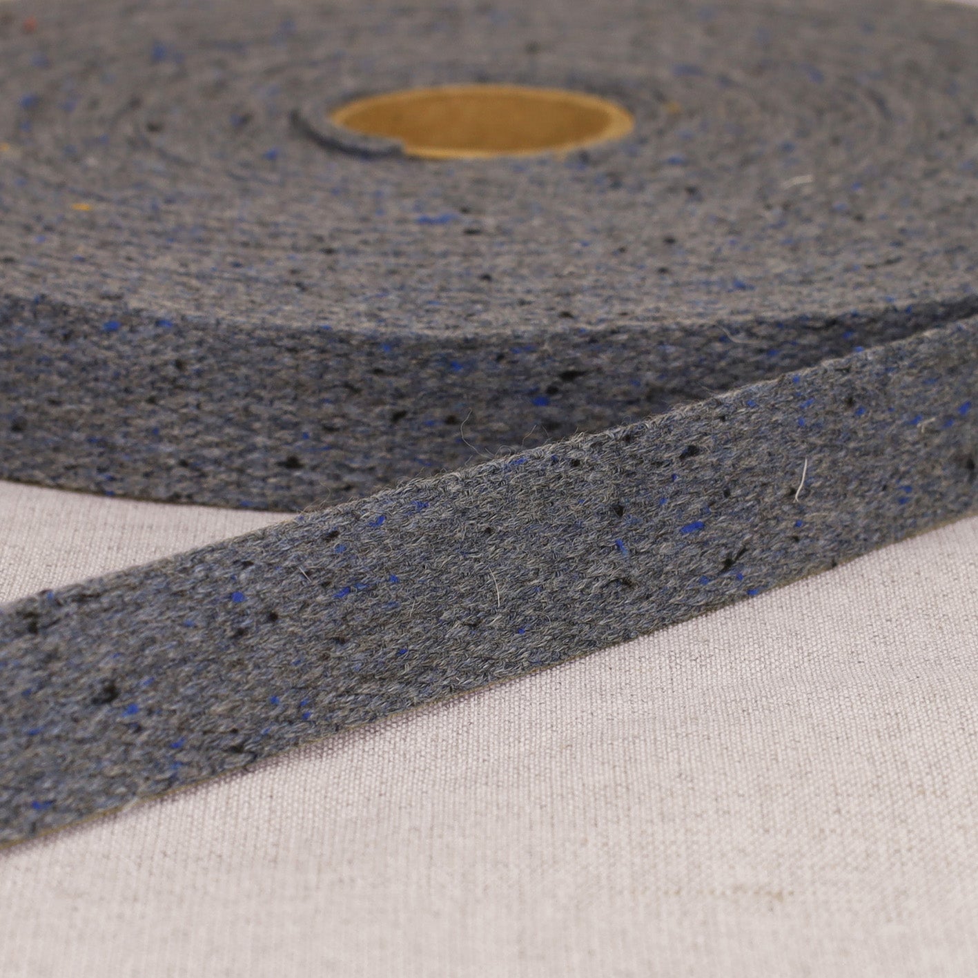 A roll of 20mm mottled grey polyester webbing strap with blue and black flecks.