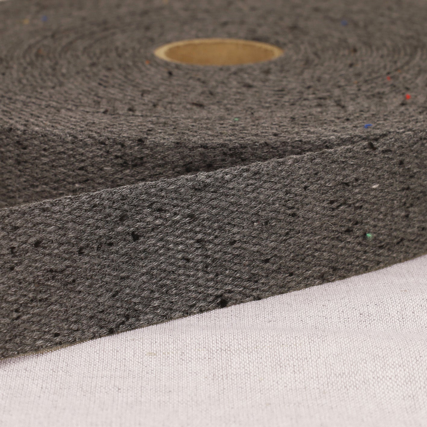 A roll of 20mm mottled grey polyester webbing strap with a textured weave and colorful flecks.