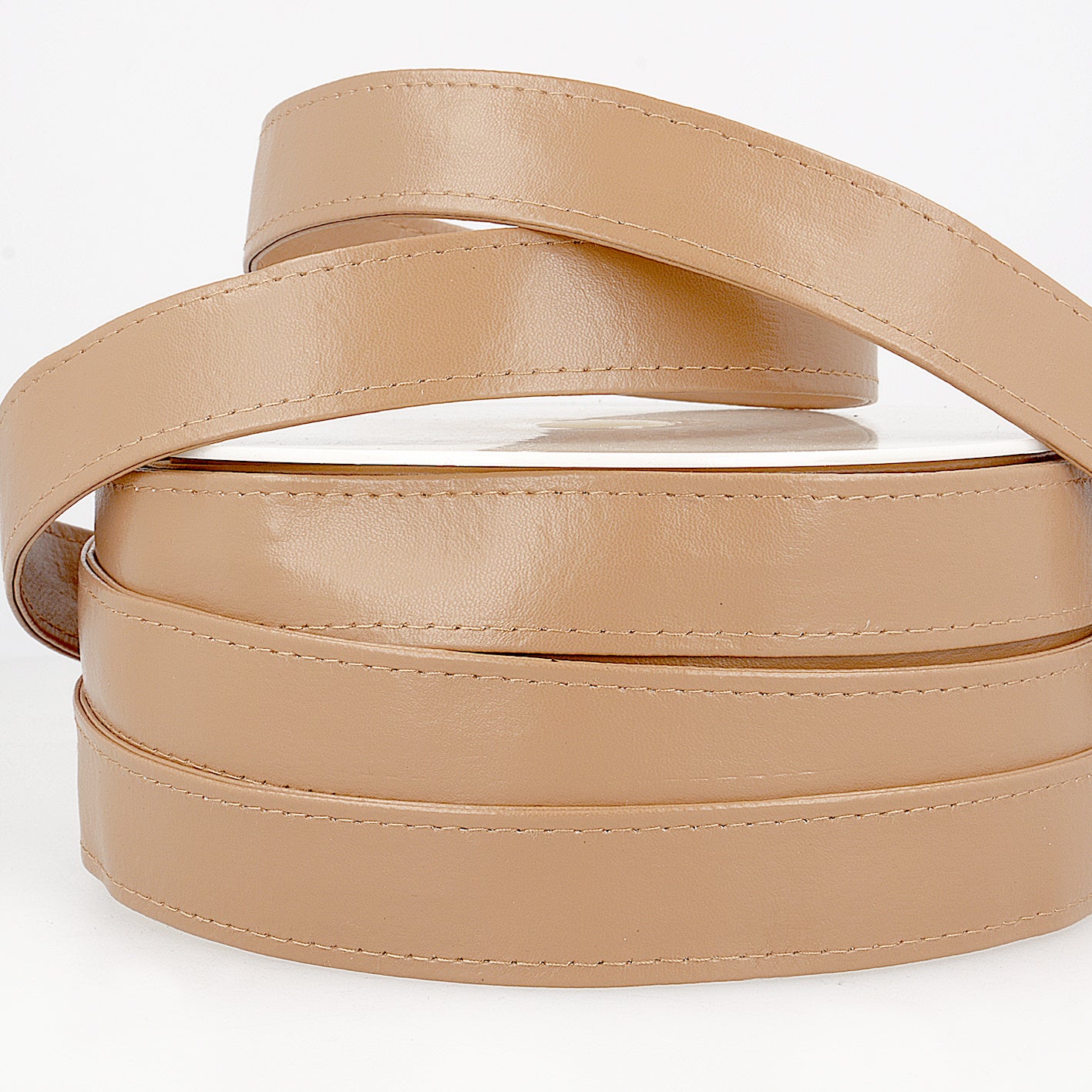 Linen-colored faux leather webbing trim with topstitched edges coiled on a white background.