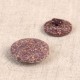 Two round, textured purple buttons made from rice husk and polyester shown from front and back.