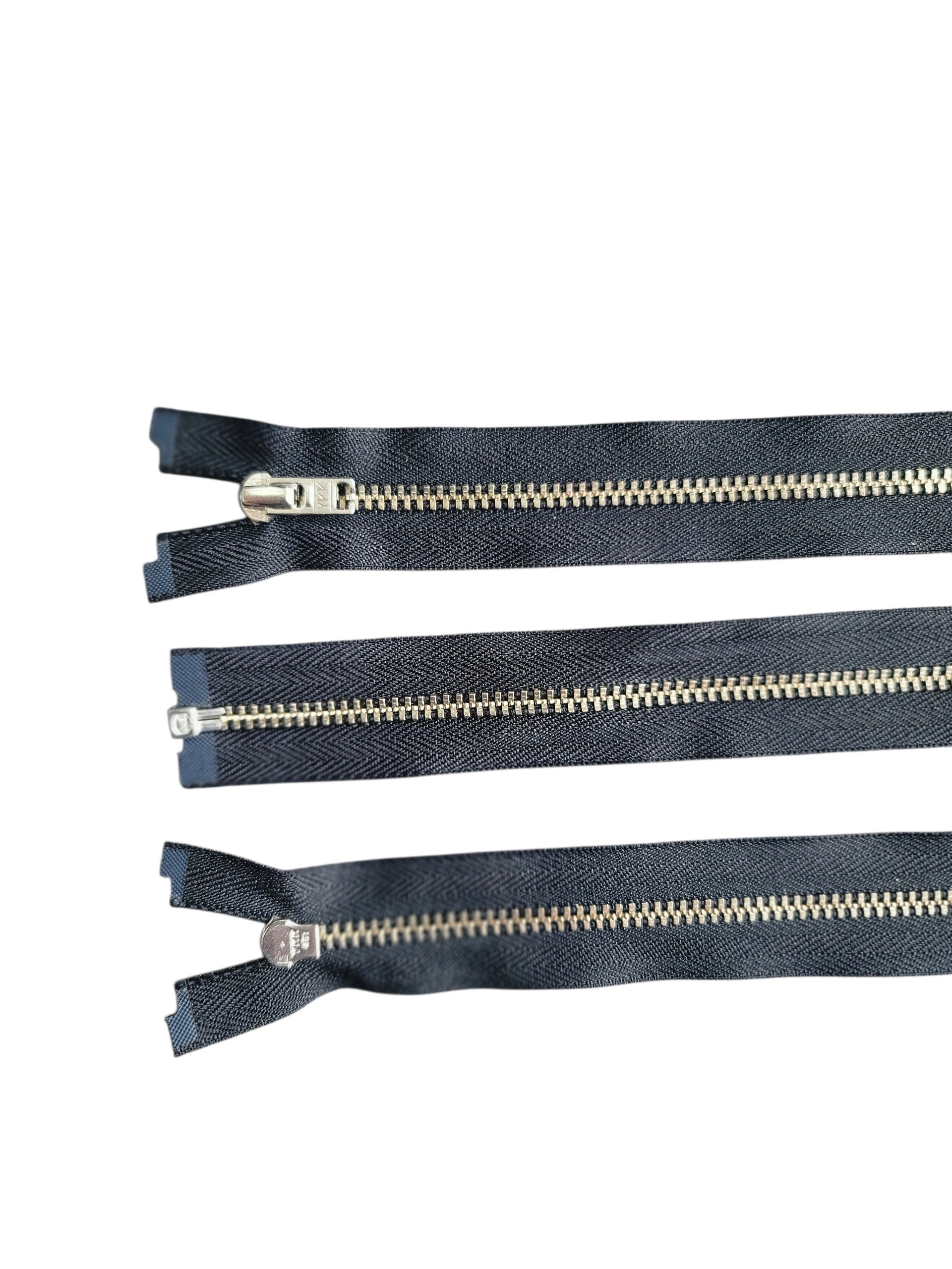 Three YKK size 3 silver metal open-end zippers with black tape shown from different angles.