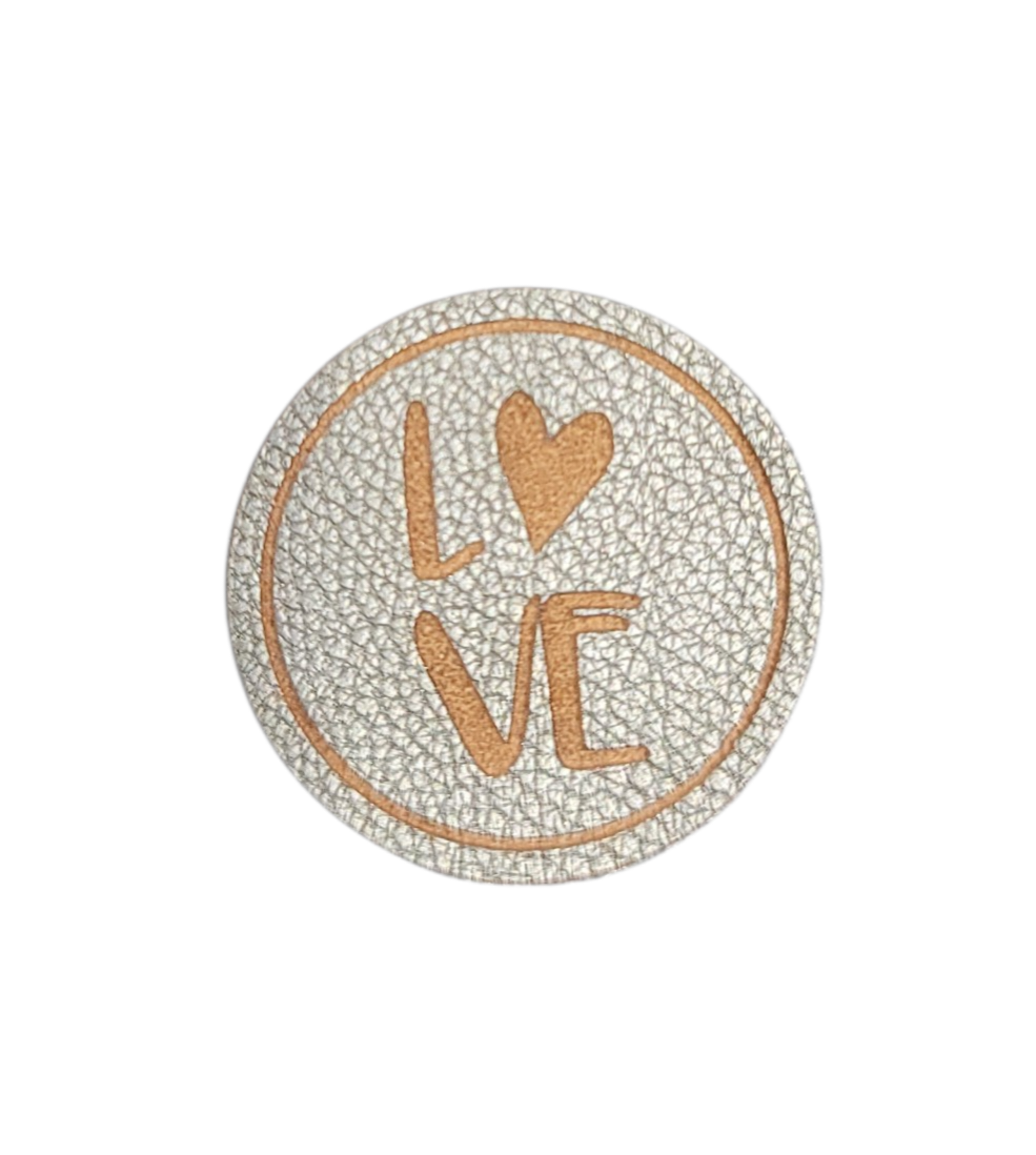 A circular silver leather iron-on patch with an embossed tan LOVE design and heart.
