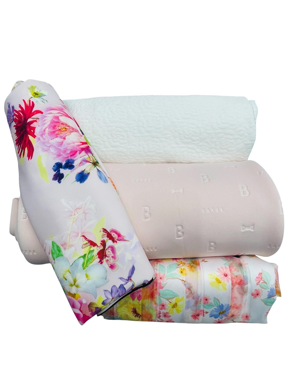 A stack of four rolled fabric remnants featuring various floral prints and embossed textures.