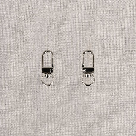 Two silver metal swivel hook clips are shown side-by-side against a light grey textured background.